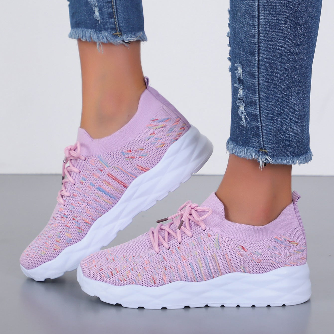 Damen Sneaker in Rosa, gestricktes Obermaterial, weiße Sohle, modisch, bequem, ideal für Freizeit und Sport, getragen mit blauen Jeans.