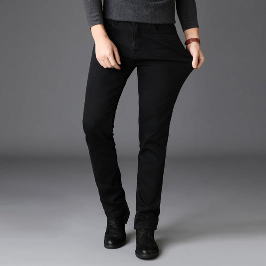 Dunkle Jeanshose, getragen von einer Person, kombiniert mit schwarzen Stiefeln und grauem Pullover. Modetrend, bequeme Passform, stilvolle Kleidung.