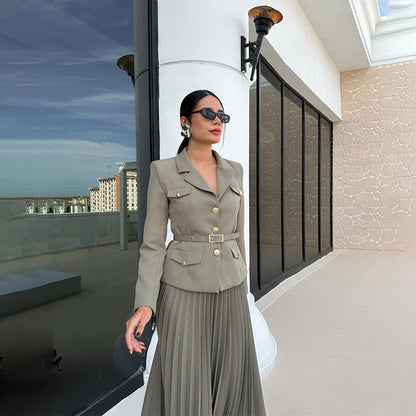 Elegante Frau in grauem Anzug mit Sonnenbrille auf Balkon, moderne Architektur im Hintergrund, stilvolle Mode, Business-Look, urbane Umgebung.