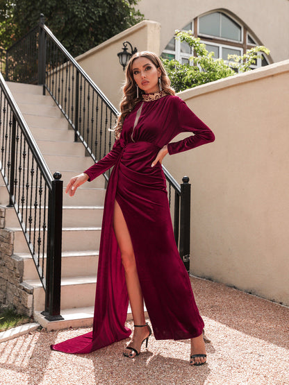 Frau in elegantem, langem, weinrotem Kleid mit hohem Schlitz posiert auf Treppe. Abendmode, Glamour, Modefotografie, luxuriöses Design.