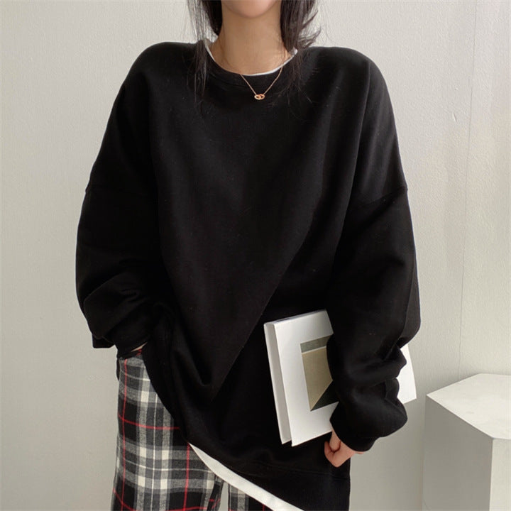 Frau in schwarzem Oversize-Pullover hält Buch, trägt karierte Hose. Modetrend, lässiger Stil, Herbstmode, gemütlicher Look.