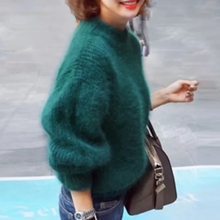 Frau in grünem Strickpullover, lächelnd, mit brauner Umhängetasche. Modetrend, Herbstmode, gemütlicher Look, Straßenstil.