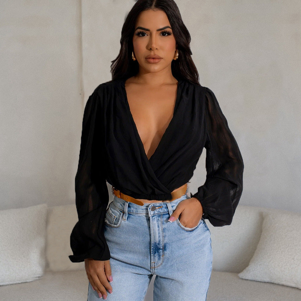 Frau in schwarzer Bluse mit tiefem Ausschnitt und blauer Jeans posiert vor beigem Hintergrund. Modetrend, Damenmode, stilvolle Kleidung.