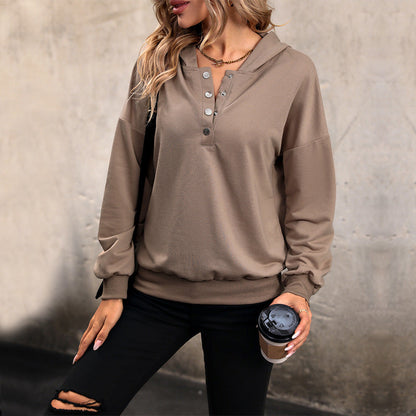 Frau in braunem Hoodie mit Knopfleiste, hält Kaffeebecher, trägt schwarze zerrissene Jeans. Streetwear, lässiger Look, modische Freizeitkleidung.