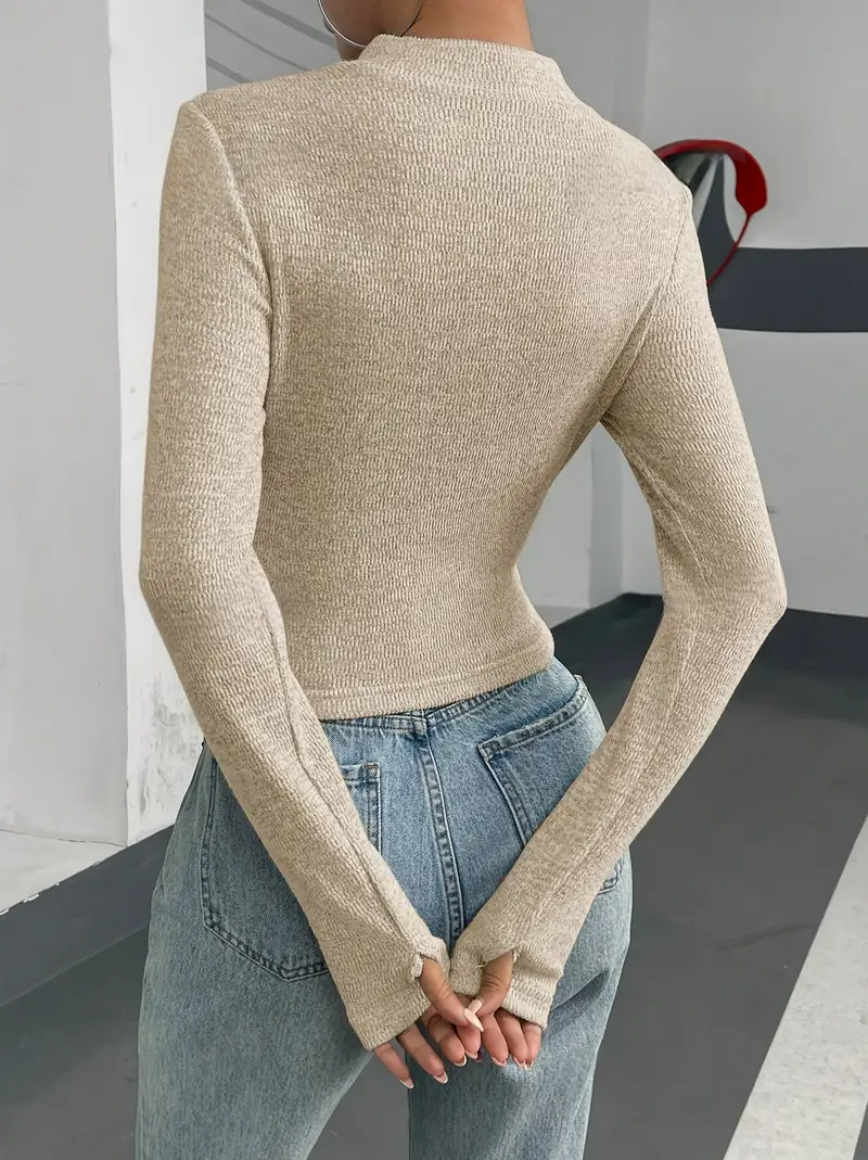 Frau in beigem, langärmligem Strickpullover und blauer Jeans, Rückansicht. Modetrend, lässiger Stil, Herbstmode, Damenbekleidung.