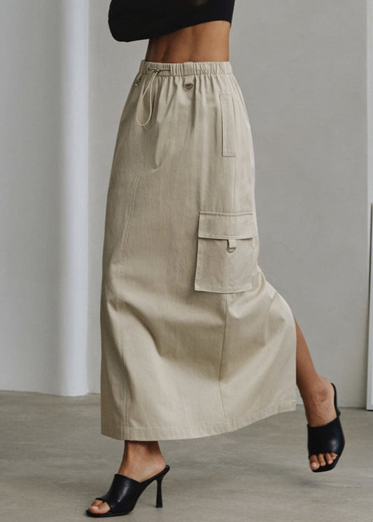 Beigefarbener Maxirock mit Seitentasche, kombiniert mit schwarzen High-Heels. Modetrend, Damenbekleidung, eleganter Look.