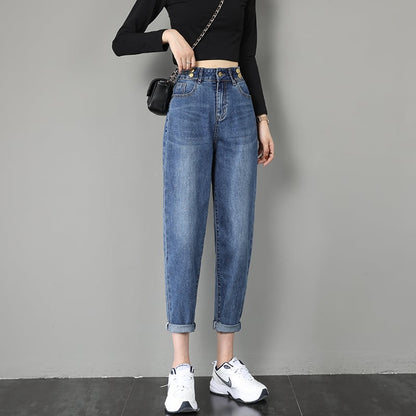 Frau in blauer Mom-Jeans, schwarzem Langarmshirt und weißen Sneakers vor grauer Wand. Modetrend, lässiger Stil, Damenmode, Streetwear.