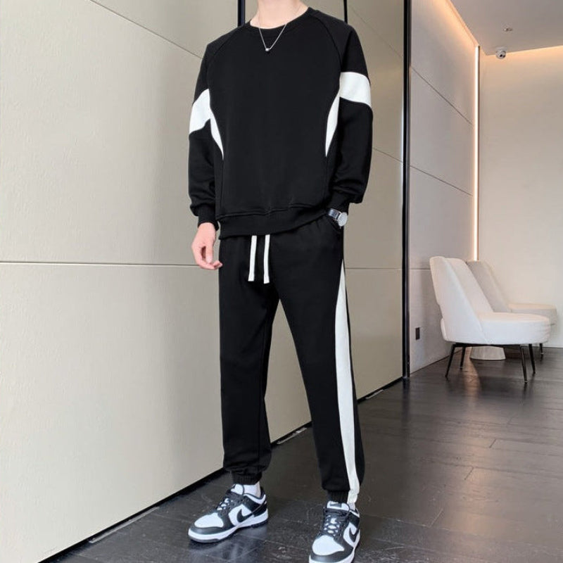 Mann in schwarzem Trainingsanzug mit weißen Streifen, trägt modische Sneakers. Moderner Freizeitlook, ideal für sportliche Aktivitäten und Streetwear.