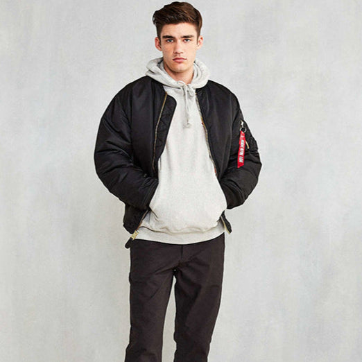 Junger Mann in schwarzer Bomberjacke und grauem Hoodie, lässiger Streetwear-Look, Mode für Herren, urbaner Stil, trendige Freizeitkleidung.