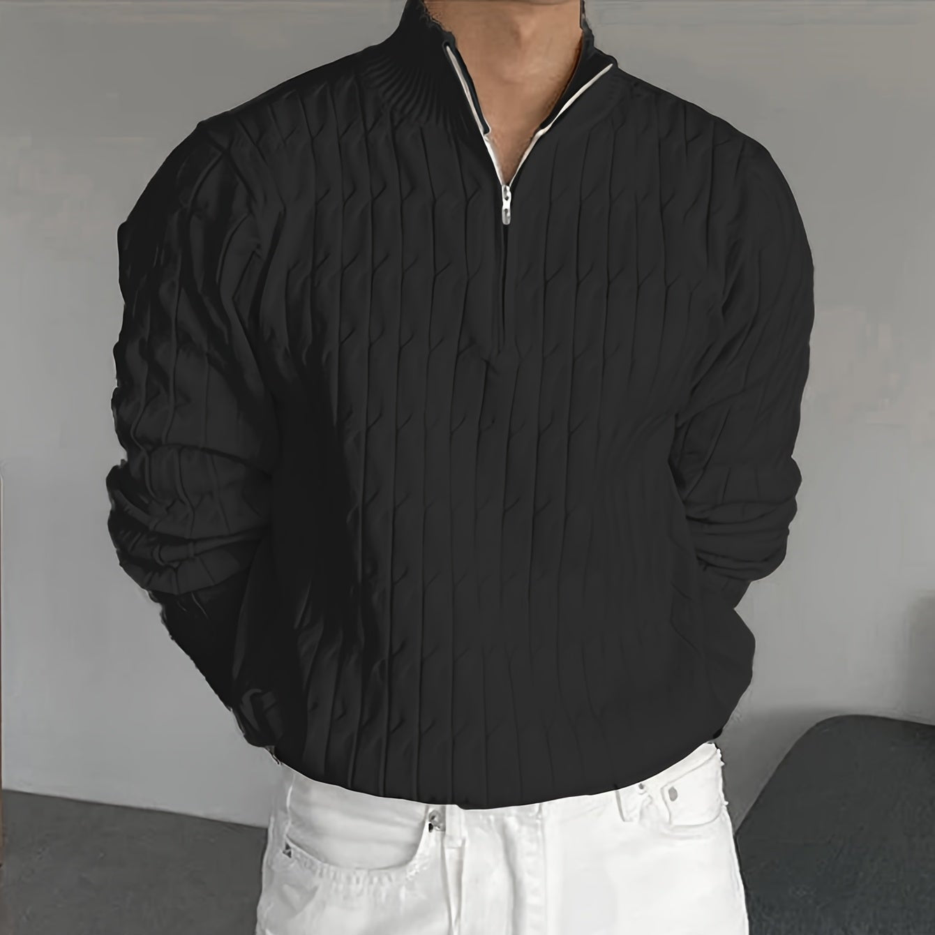 Schwarzer Strickpullover mit Reißverschluss, getragen von einer Person in weißer Hose. Modischer Herrenpullover, elegantes Design, Herbstmode.