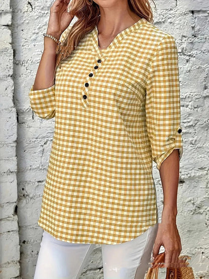 Gelbes kariertes Damenhemd mit Knopfleiste, 3/4-Ärmeln und V-Ausschnitt, kombiniert mit weißen Hosen. Perfekt für lässige Frühlings- und Sommermode.
