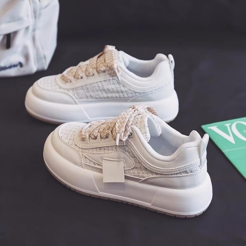 Weiße Sneaker mit dicker Sohle und geflochtenen Schnürsenkeln auf dunklem Hintergrund, modisch und modern, ideal für Streetwear-Looks.