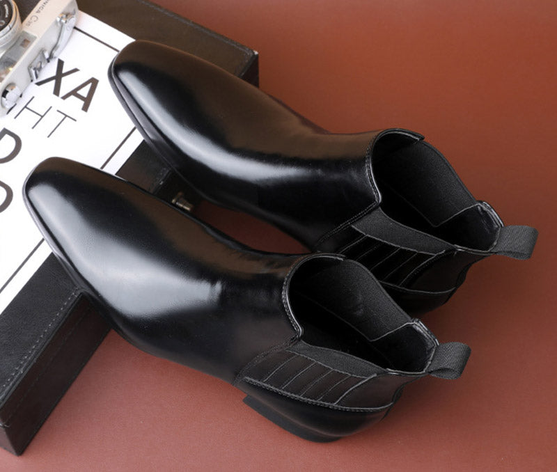 Schwarze Chelsea-Stiefel aus Leder auf braunem Hintergrund, stilvoll und elegant, ideal für Herrenmode und Business-Outfits.