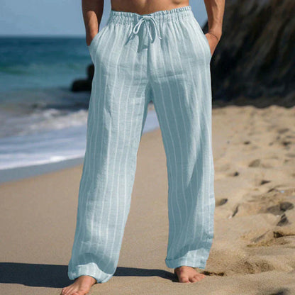 Person in hellblauer Leinenhose am Strand, entspannte Sommermode, lässige Strandkleidung, bequeme weite Hose, Urlaub am Meer.
