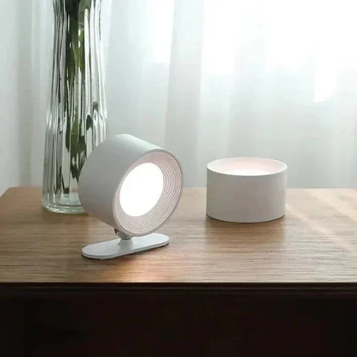 Weiße LED-Tischlampe auf Holzoberfläche neben Vase mit Blumen. Modernes, minimalistisches Design, ideal für stilvolle Inneneinrichtung.