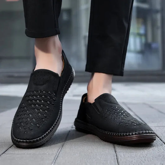 Schwarze Herren-Slipper aus Leder mit perforiertem Design, bequem und stilvoll, ideal für Freizeitkleidung. Perfekte Schuhe für den Alltag.