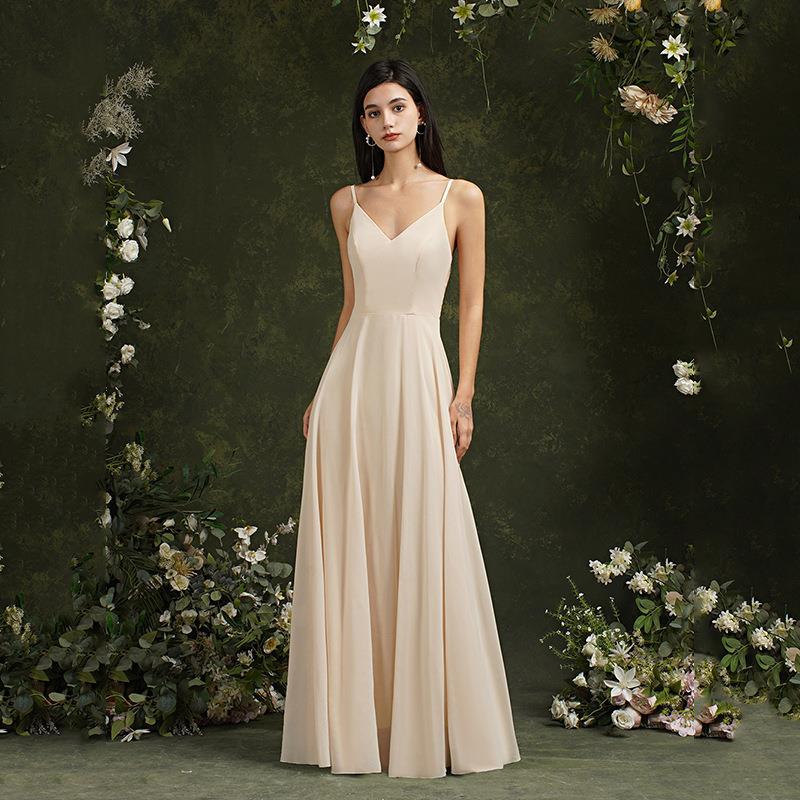 Frau in eleganter, cremefarbener Abendkleid, umgeben von Blumenarrangement, vor grünem Hintergrund. Perfekt für Hochzeiten oder formelle Anlässe.