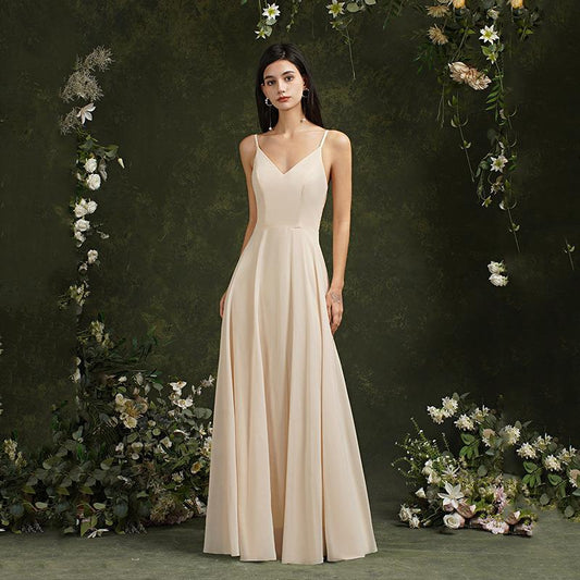 Frau in eleganter, cremefarbener Abendkleid, umgeben von Blumenarrangement, vor grünem Hintergrund. Perfekt für Hochzeiten oder formelle Anlässe.