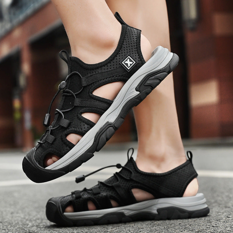 Schwarze Outdoor-Sandalen mit robustem Design und rutschfester Sohle auf Asphalt. Ideal für Wandern und Freizeitaktivitäten.