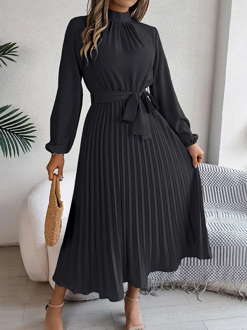 Elegantes schwarzes Plisseekleid mit langen Ärmeln und Taillengürtel, getragen von Frau mit Strohtasche. Perfekt für formelle Anlässe.