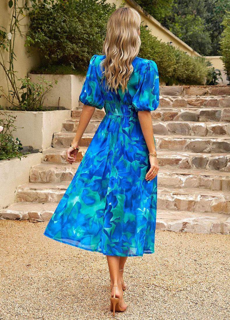 Frau in blauem Blumenkleid auf Steintreppe, Sommermode, elegantes Design, Rückansicht, blonde Haare, Outdoor, stilvoll, modisch.