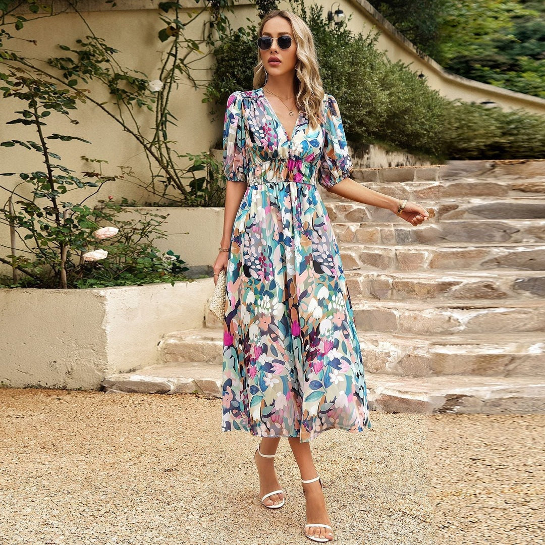 Frau in geblümtem Sommerkleid auf Steintreppe, trägt Sonnenbrille und Sandalen, umgeben von grüner Vegetation. Elegante Mode, Outdoor-Stil.