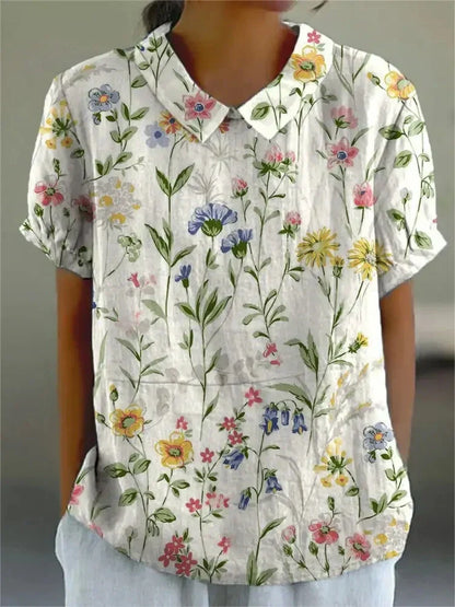 Damenbluse mit Blumenmuster, kurzärmelig, weißer Hintergrund, bunte Blumen, lässiger Stil, modische Sommerbekleidung, florales Design.