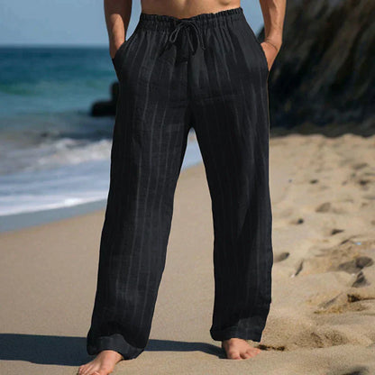 Mann in schwarzer Leinenhose am Strand, entspannte Sommermode, lässige Strandkleidung, Herrenbekleidung, Urlaubsoutfit, Freizeitlook.