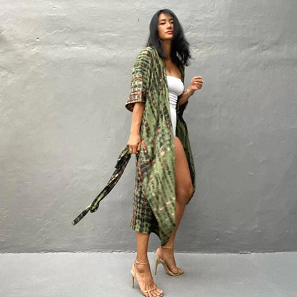 Frau in grünem Kimono und weißen Kleid posiert vor grauer Wand, trägt beige High Heels. Mode, Streetstyle, Sommeroutfit, trendige Kleidung.