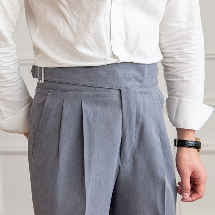 Mann in weißem Hemd und grauer, hoch taillierter Hose mit Gürtel, eleganter Business-Look, moderne Herrenmode, stilvolles Outfit.
