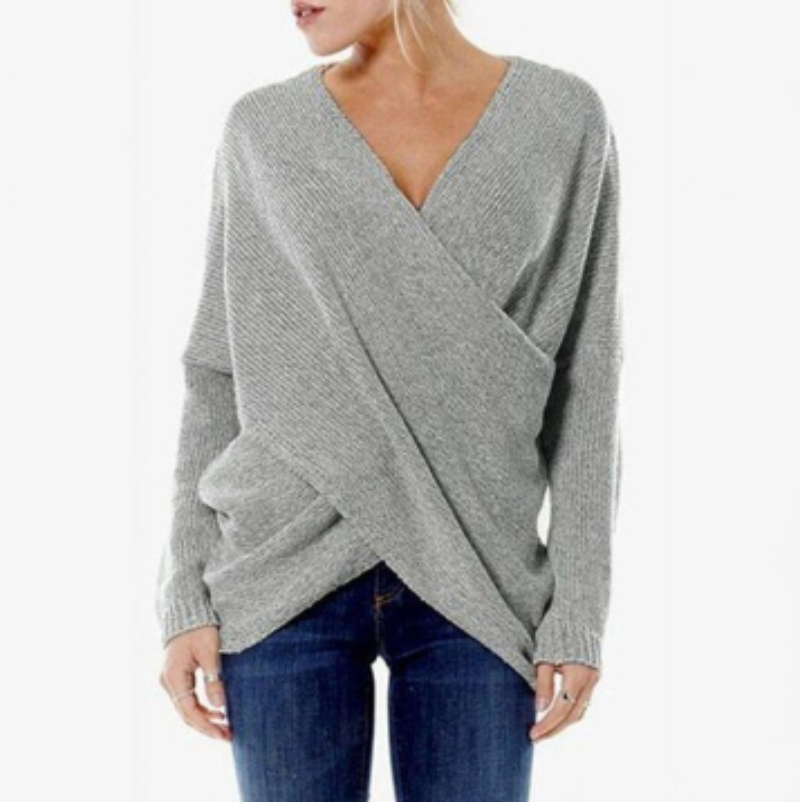 Grauer Wickelpullover Damen, V-Ausschnitt, lässig, weiches Strickmaterial, kombiniert mit blauer Jeans, modischer Herbst-Winter-Look.