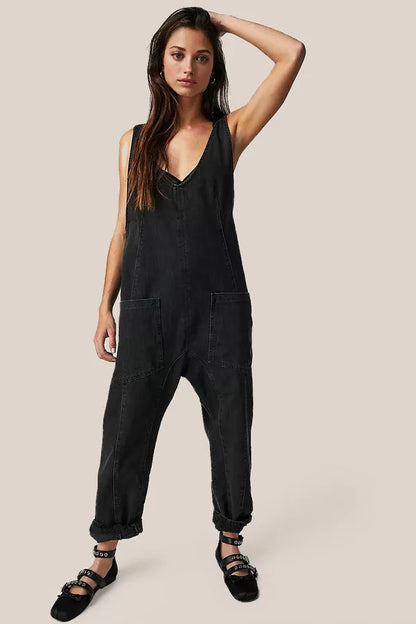 Frau in schwarzem Denim-Jumpsuit mit V-Ausschnitt und Taschen, lässiger Look, modische Damenbekleidung, trendiger Einteiler, schwarze Schuhe.