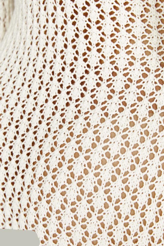 Nahaufnahme eines weißen, gehäkelten Stoffmusters mit feinen, symmetrischen Maschen. Ideal für Mode, Handarbeit und DIY-Projekte.