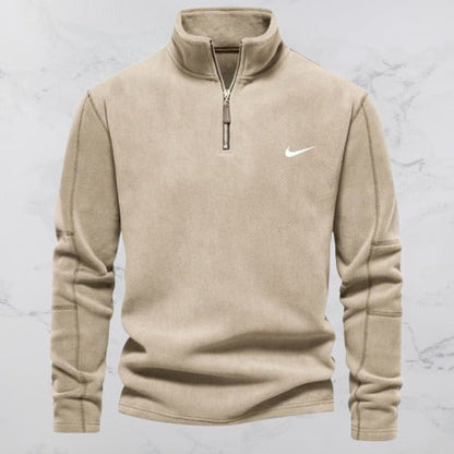 Beige Nike Fleece-Pullover mit Reißverschluss, Langarm, Stehkragen, auf Marmorhintergrund. Sportbekleidung, Herrenmode, Freizeitlook.