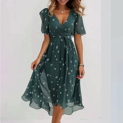 Frau in elegantem, grünem Sommerkleid mit Blumenmuster, V-Ausschnitt und kurzen Ärmeln. Perfekt für Damenmode, Freizeitkleidung, Sommeroutfits.