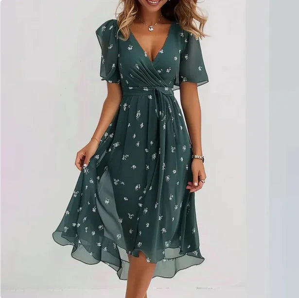 Frau in elegantem, grünem Sommerkleid mit Blumenmuster, V-Ausschnitt und kurzen Ärmeln. Perfekt für Damenmode, Sommerkleider, Freizeitkleidung.