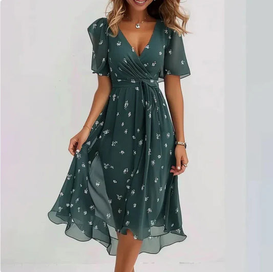 Frau in elegantem, grünem Sommerkleid mit Blumenmuster, V-Ausschnitt und kurzen Ärmeln. Perfekt für Damenmode, Sommerkleider, Freizeitkleidung.
