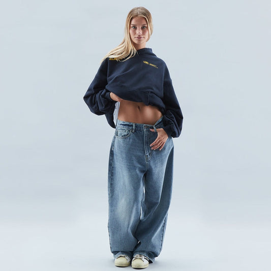 Frau in weitem Jeans und dunklem Hoodie, lässiger Streetwear-Look, modische Oversized-Kleidung, trendige Freizeitmode, urbaner Stil.