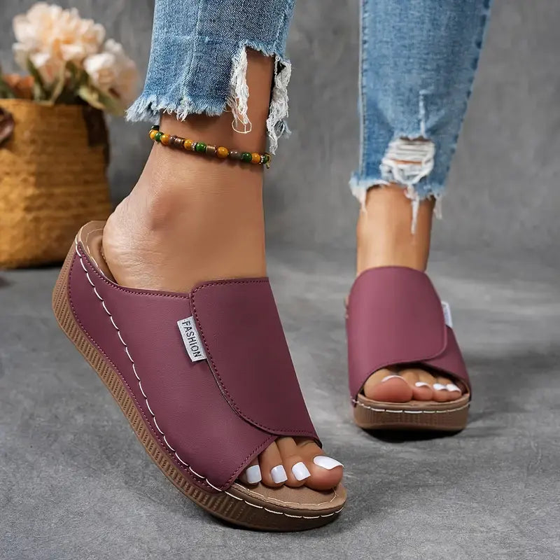 Damen tragen lila Sandalen mit Keilabsatz und offener Spitze, kombiniert mit zerrissenen Jeans. Modische Sommerschuhe, bequem und stilvoll.