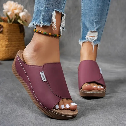 Damen tragen lila Sandalen mit Keilabsatz und offener Spitze, kombiniert mit zerrissenen Jeans. Modische Sommerschuhe, bequem und stilvoll.