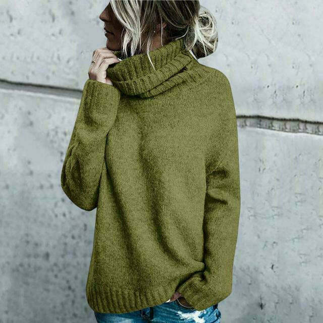Frau in olivgrünem Rollkragenpullover, lässig vor grauer Betonwand. Modetrend, Herbstmode, Strickpullover, Damenbekleidung.