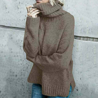 Frau in braunem Strickpullover mit Rollkragen, lässig gekleidet, vor grauer Betonwand. Modetrend Herbst/Winter, gemütlicher Look.