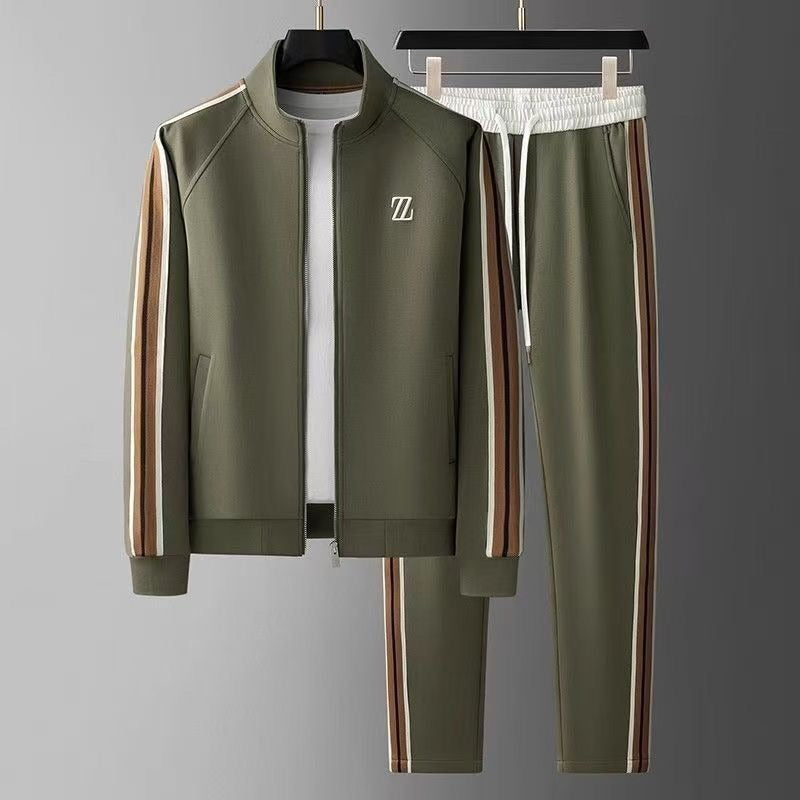 Grüner Trainingsanzug mit weißen und braunen Streifen, bestehend aus Jacke und Hose, auf grauem Hintergrund. Sportbekleidung, Freizeitmode.