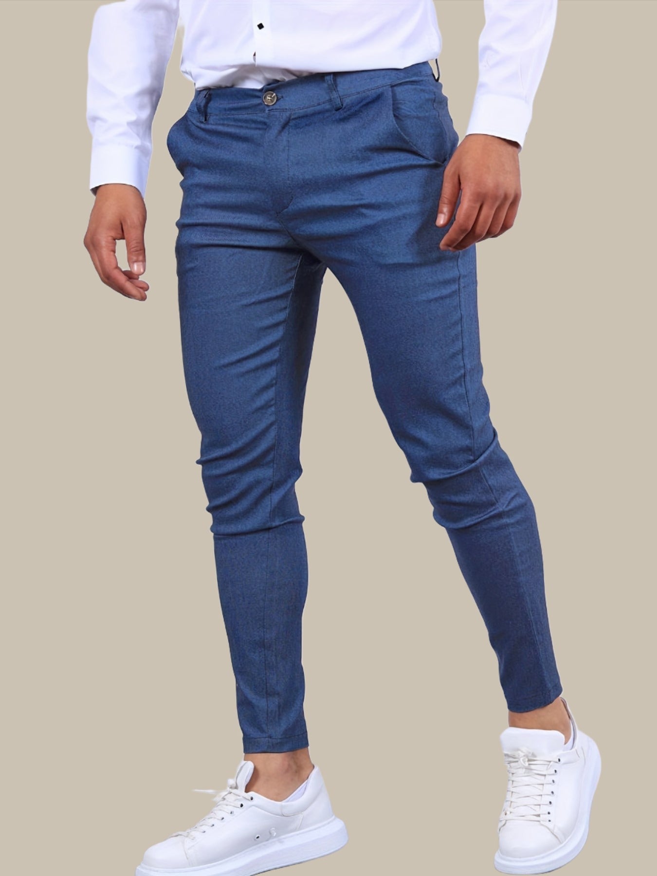 Mann in blauer Slim-Fit-Hose und weißem Hemd, kombiniert mit weißen Sneakers. Modische Herrenbekleidung, eleganter Freizeitlook.