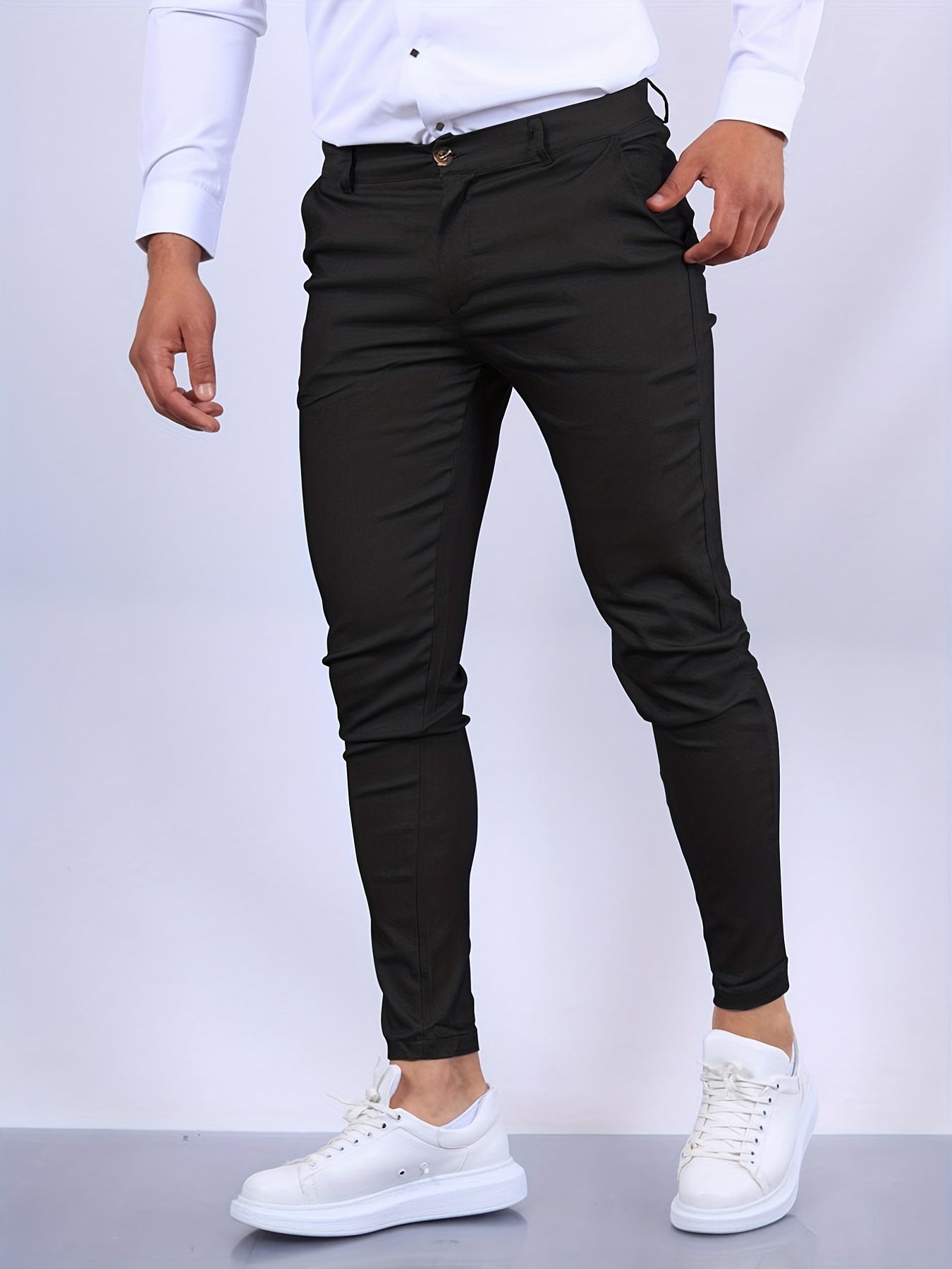 Mann in schwarzer Slim-Fit-Hose und weißen Sneakers, weißes Hemd. Modische Herrenbekleidung, eleganter Look, stilvolle Freizeitmode.