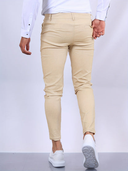Mann in beiger Chinohose und weißem Hemd, von hinten fotografiert, geht auf grauem Boden. Elegante Herrenmode, Freizeitlook, stilvolle Kleidung.