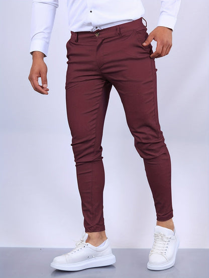 Mann in burgunderroter Slim-Fit-Hose und weißem Hemd, kombiniert mit weißen Sneakern. Elegante Herrenmode, stilvoll und modern.