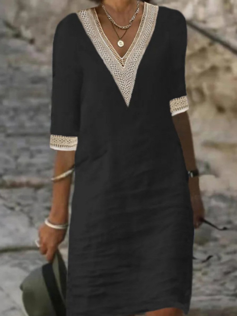 Frau in schwarzem Kleid mit Spitzenbesatz, V-Ausschnitt und Dreiviertelärmeln, hält Hut. Elegantes Sommeroutfit auf gepflastertem Weg.