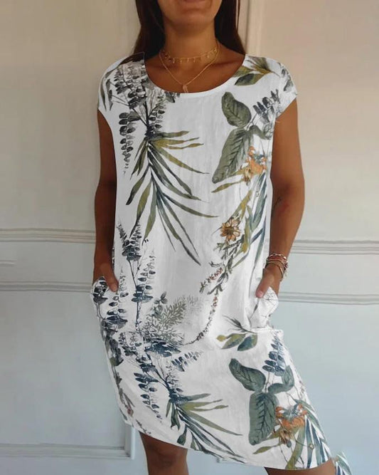 Frau in weißem Sommerkleid mit tropischem Blumenmuster, kurzen Ärmeln und Taschen. Perfekt für lässige Sommermode und Strandoutfits.