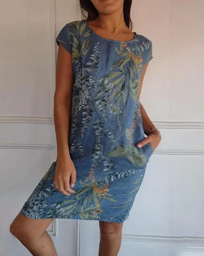 Frau in blauem Sommerkleid mit floralen Mustern, knielang, kurzärmelig, lässiger Stil. Perfekt für Freizeitmode und sommerliche Outfits.
